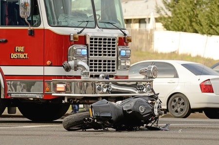 A wrecked motorcycle with a fire truck in the background