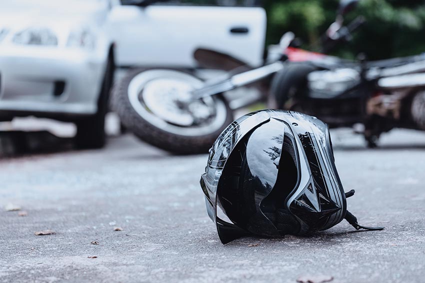 Black helmet in the foreground and wrecked motorcycle